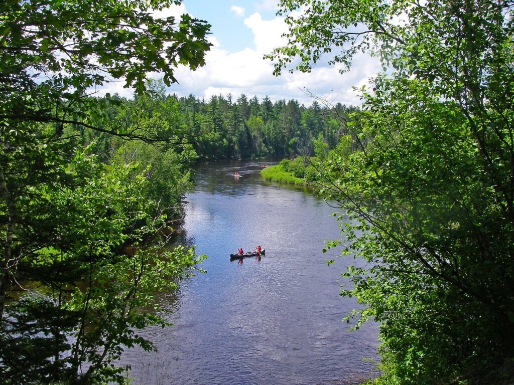 Canoe on the Au Sable River between wooded banks in the Huron-Manistee National Forest