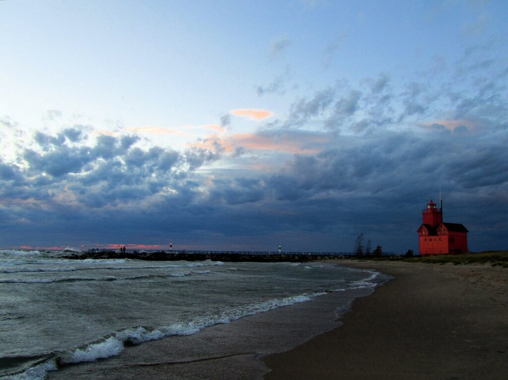 Big Red, the Holland Harbor Light, at dusk beyond waves rolling onto a Lake Michigan beach