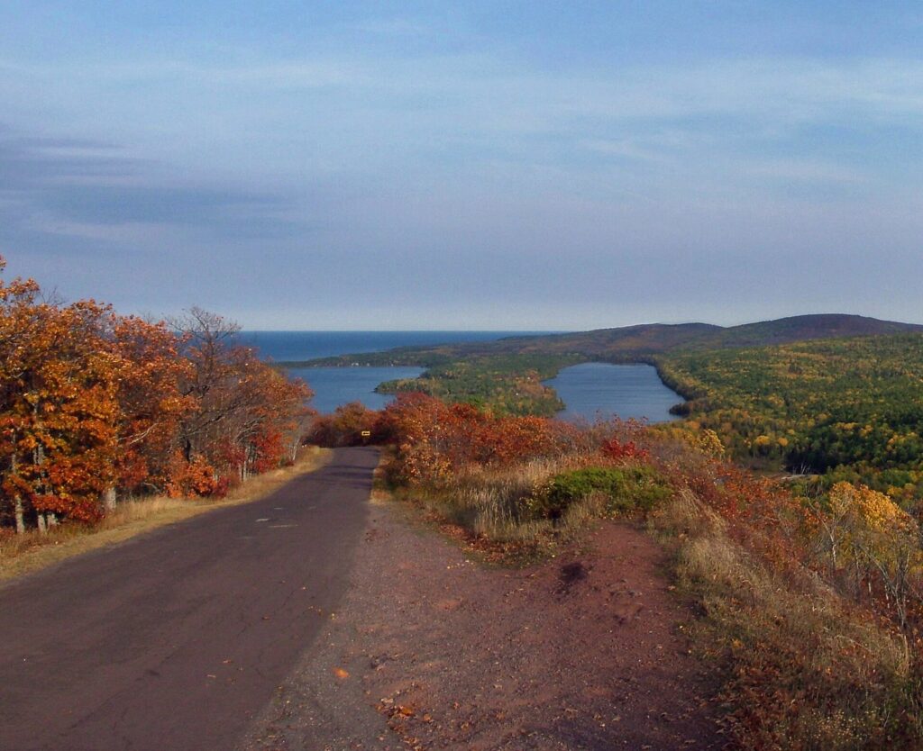 Brockway Mountain Drive running along a ridge of orange and red trees above inland lakes and Lake Superior
