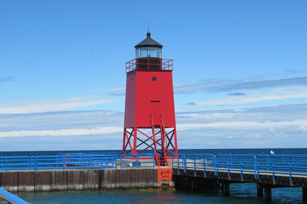 Red South Pier Light on its steel legs at the end of the Charlevoix pier under a blue sky