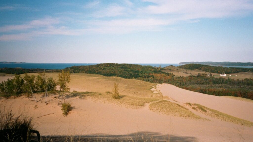 View from the top of the Dune Climb over rolling sand and dune grass toward forest and distant water