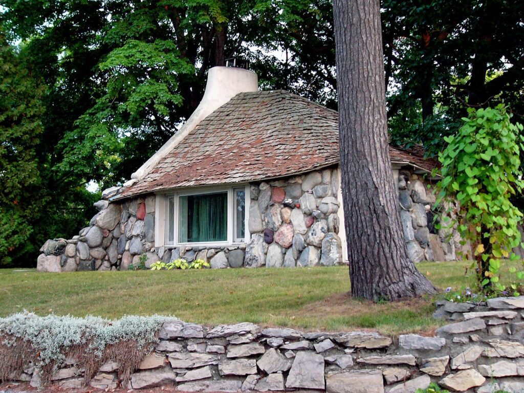 Stone cottage with a curving shingled roof and fieldstone walls, one of Earl Young's houses in Charlevoix