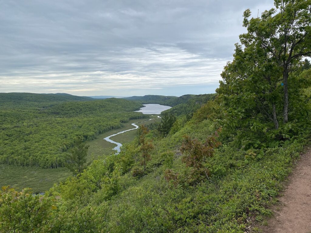 Hiking path on the ridge above the Big Carp River as it winds toward Lake of the Clouds through green forest