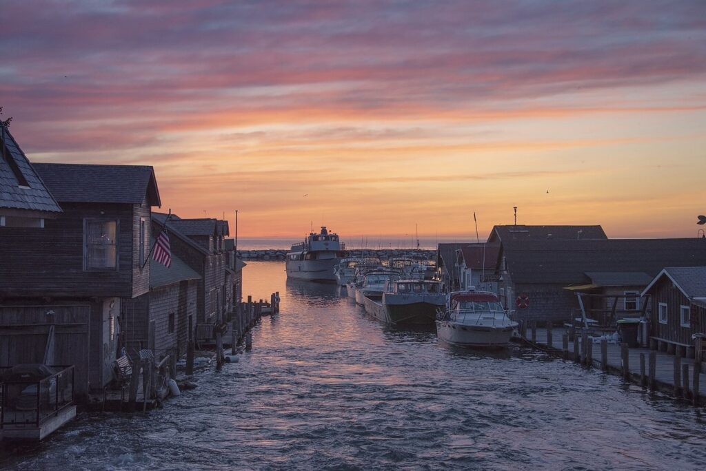 Weathered wooden fishing shanties and docked boats along a river channel at sunset