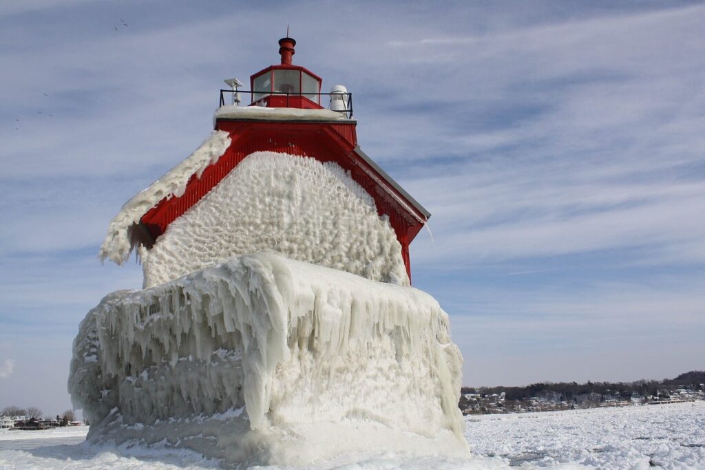 Grand Haven's red outer pier light encased in thick storm ice, with the frozen Lake Michigan shore behind