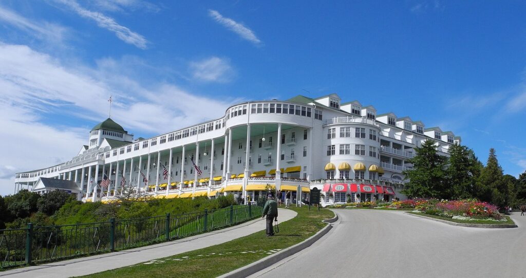 The Grand Hotel's long white porch with yellow awnings above a curving drive and flower beds