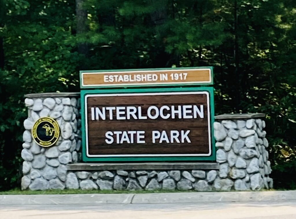 Stone and wood entrance sign for Interlochen State Park reading Established in 1917