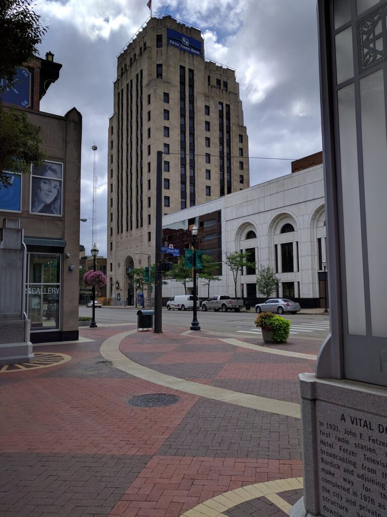 Brick-paved pedestrian street in downtown Kalamazoo with a tall art deco office tower behind
