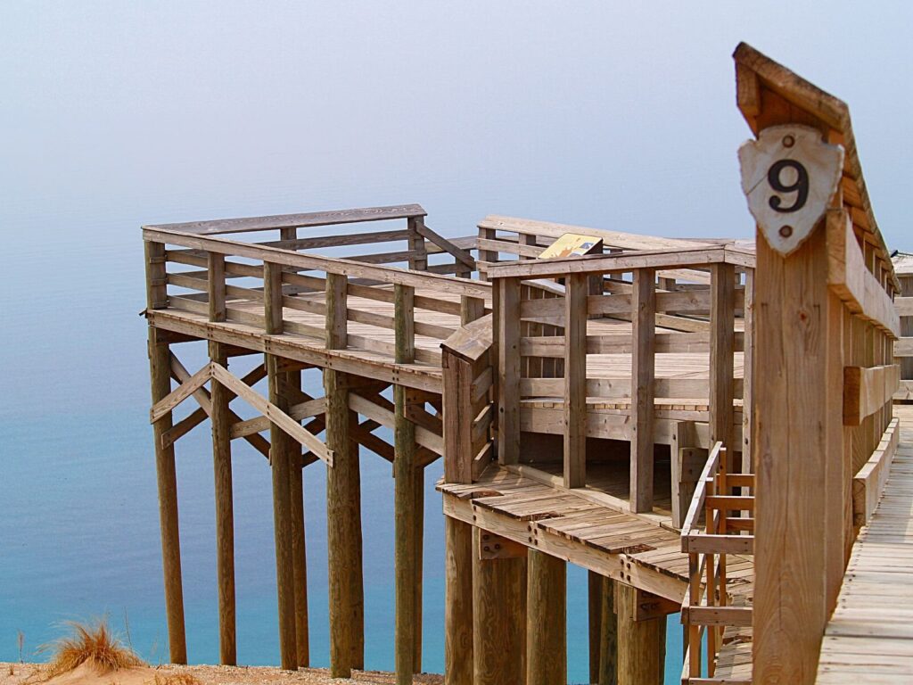 Wooden viewing platform marked with the number 9 above a steep sand bluff and blue Lake Michigan water
