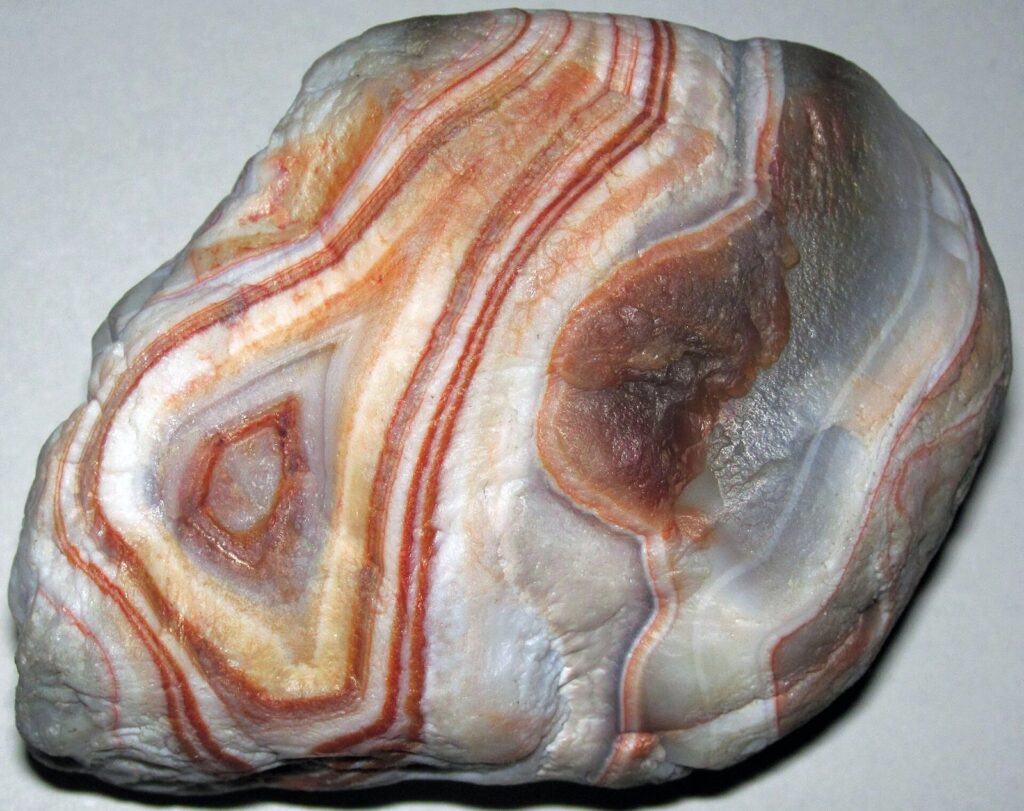 Polished Lake Superior agate with concentric bands of red, orange, white and gray