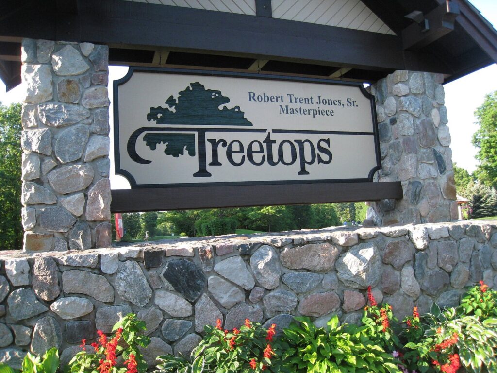 Stone entrance sign for the Robert Trent Jones Sr. Masterpiece course at Treetops, with red flowers below