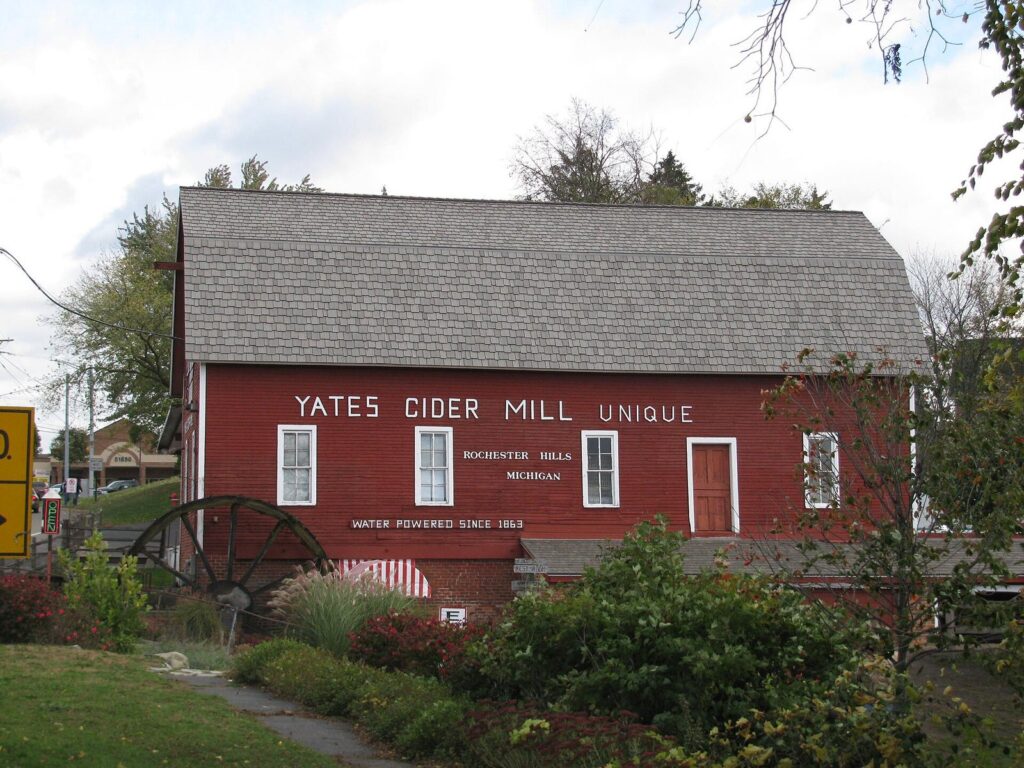 Red wooden Yates Cider Mill building with a water wheel and a sign reading Yates Cider Mill